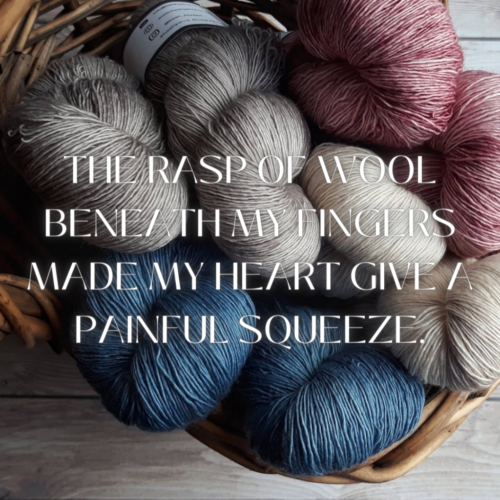 A basket of red, beige, and blue yarn overlaid with the words "The rasp of wool beneath my fingers made my heart give a painful squeeze."