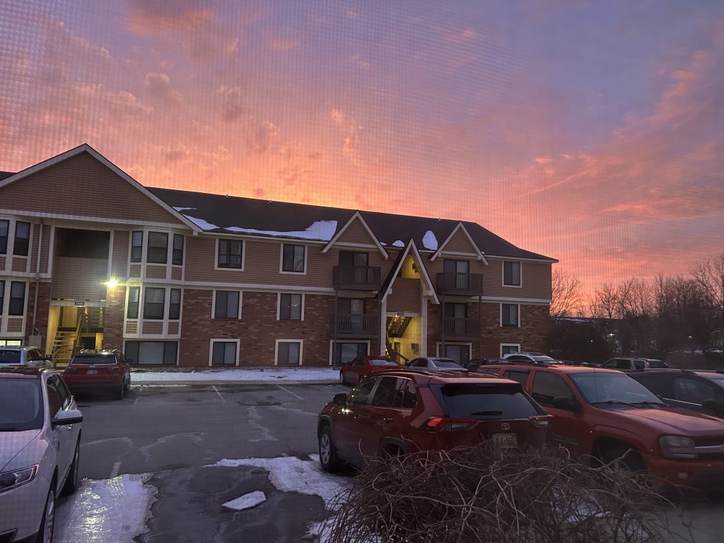 A pinkish orange winter sunrise over an apartment building.