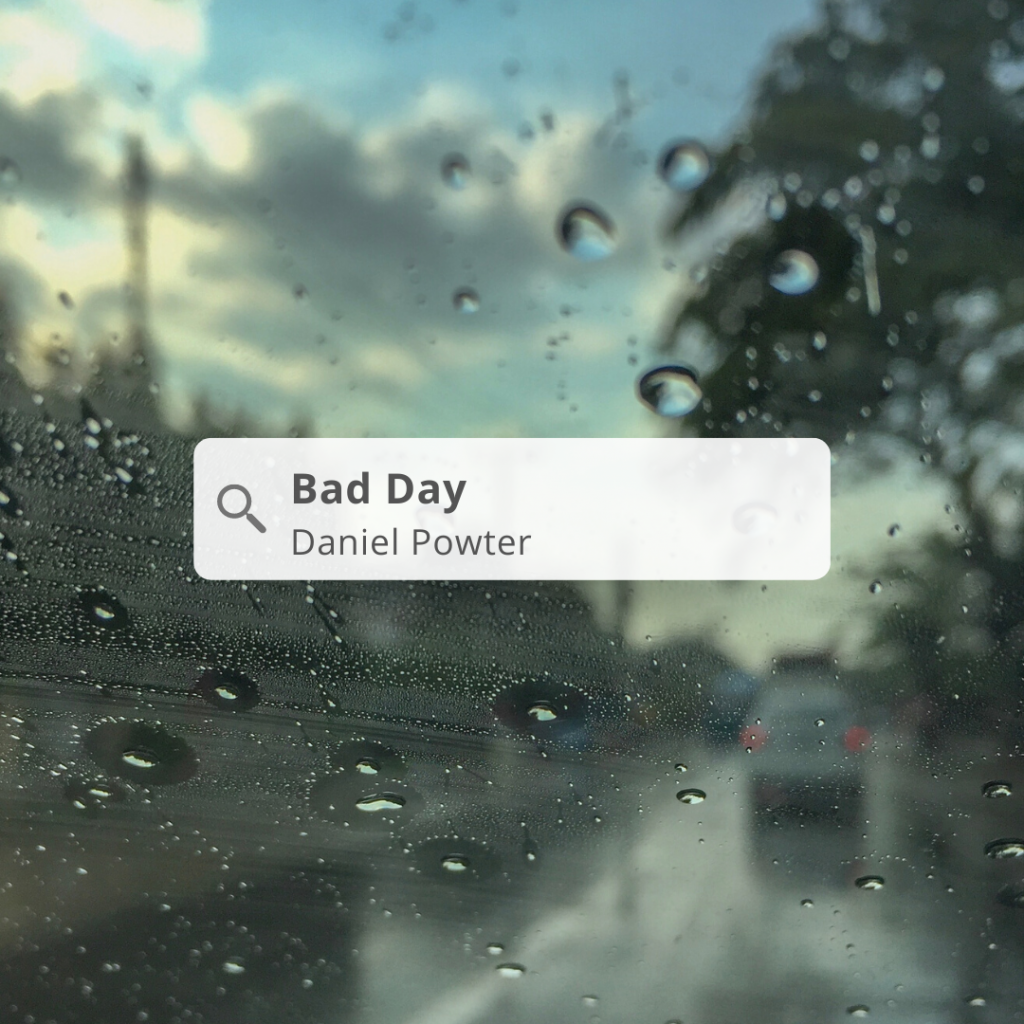 A rainy street through a wet windshield. A search box has the words "Bad Day Daniel Powter"