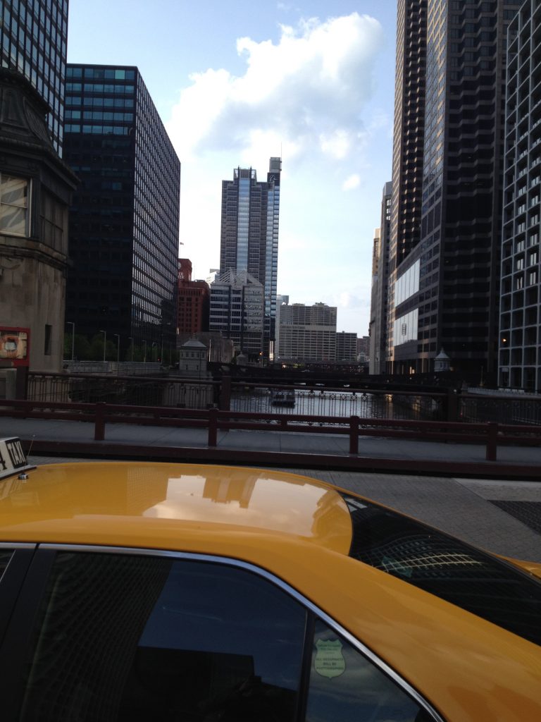 View of Chicago from street level, looking over the Chicago River over the top of a cab.