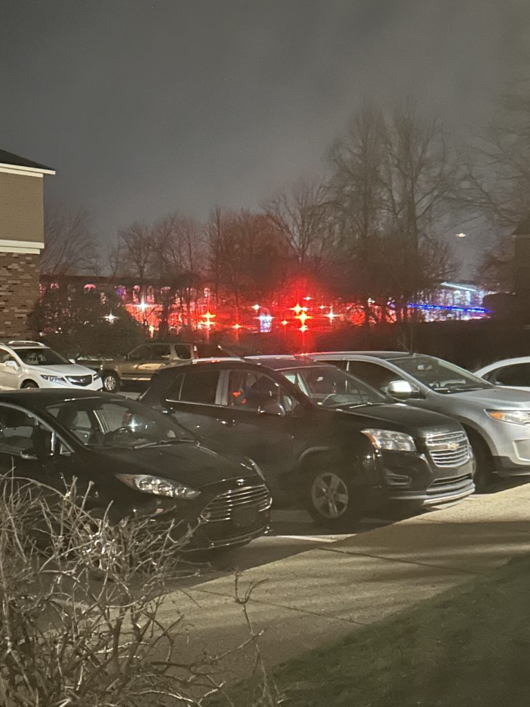 Emergency vehicle lights seen at a distance over a parking lot.